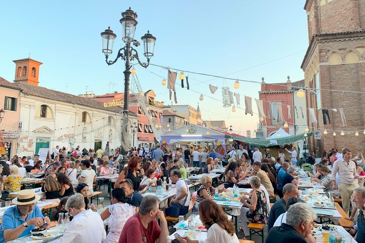 Immagine della Sagra del Pesce con stand gastronomici e visitatori che degustano piatti tipici